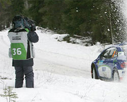 En rallybil kör nedför en snöig väg. (AI text)