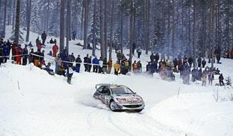 En rallybil kör nerför en snöig backe. (AI text)