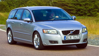 En silverfärgad Volvo V40 kombi kör längs en landsväg. (AI text)