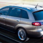 En silverbil kör nerför en väg. (AI text)