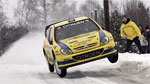 En gul rallybil kör nedför en snöig väg. (AI text)