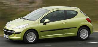 En grön Peugeot 208 kör nedför en väg. (AI text)