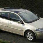 En silverfärgad bil parkerad vid en vägkant. (AI text)
