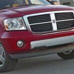 En röd Dodge Ram SRT-utanlastigt fordon parkerad framför ett byggnad. (AI text)