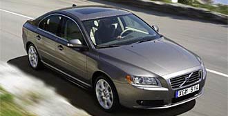 En Volvo S60 sedan kör nerför en väg. (AI text)