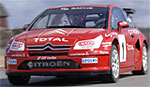 En röd Citroën C3 rallybil kör ner en väg. (AI text)