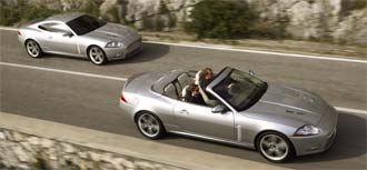 Två silver Jaguar XKR cabriolet kör nedför en bergsväg. (AI text)