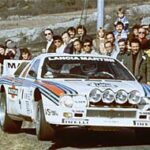 En rallybil står parkerad framför en skara människor. (AI text)