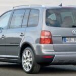 En silverfärgad Volkswagen Touran parkerad vid vägkanten. (AI text)
