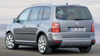 En silverfärgad Volkswagen Touran parkerad vid vägkanten. (AI text)