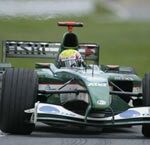 En grön Formel 1-bil körs längs banan. (AI text)