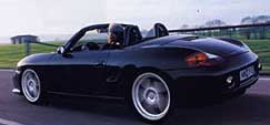 En svart Porsche Boxster kör nerför en väg. (AI text)