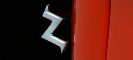 En röd bil med ett chromade dörrratt. (AI text)