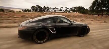 En Porsche Cayman GTS kör nerför en grusväg. (AI text)