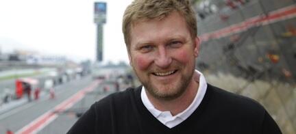 En man leende framför en racerbana. (AI text)