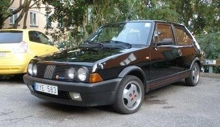 En svart bil parkerad i en parkeringsplats. (AI text)