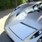 En silverfärgad sportbil parkerad i en uppfart. (AI text)