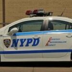 En NYPD-polisbil parkerad framför ett byggnad. (AI text)