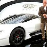 En man står bredvid en vit sportbil. (AI text)