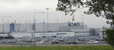 En fabrik med bilar parkerade framför den (AI text)