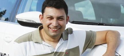 En man lutar sig mot en vit bil. (AI text)