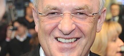 En man i kostym och slips leder ett vänligt leende. (AI text)