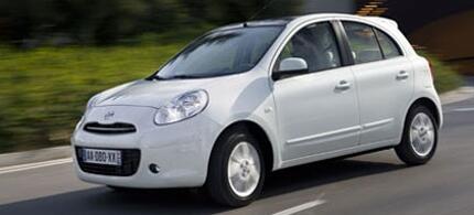 En vit bil körer ner en gata. (AI text)