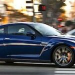 En blå Nissan GT-R kör ner på gatan. (AI text)