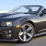En svart Chevrolet Camaro cabriolet parkerad i en parkeringsplats. (AI text)