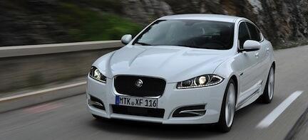 En vit Jaguar XF kör nerför en bergsväg. (AI text)