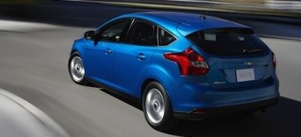 En blå Ford Focus kör nedför en väg. (AI text)