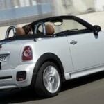 En vit Mini Cooper cabriolet kör på en racerbana. (AI text)