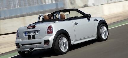 En vit Mini Cooper cabriolet kör på en racerbana. (AI text)