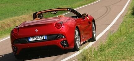 En röd Ferrari California kör längs en landsväg. (AI text)