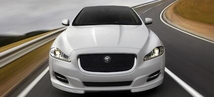 En vit Jaguar XF kör ner en väg. (AI text)