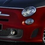 En röd Fiat 500 parkerad på gatan. (AI text)