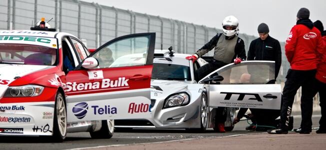 En grupp personer står omkring en racebil. (AI text)