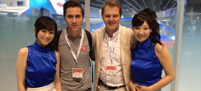 En grupp personer poserar för en foto på en bilmesse. (AI text)