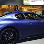 En kvinna står bredvid en blå sportbil. (AI text)