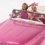 En rosa cabriolet med två tjejer ombord. (AI text)