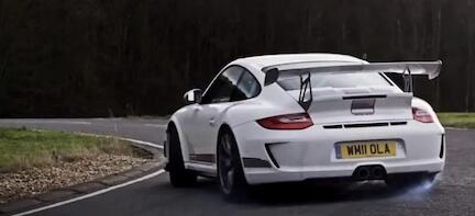 En vit Porsche 911 GT3 RS körs längs en väg. (AI text)