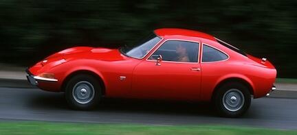 En röd sportbil kör nerför en väg. (AI text)