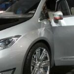 En silverfärgad bil med öpprat däck på en bilsalong. (AI text)