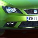 En grön bil parkerad i en parkeringsplats (AI text)