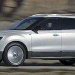 En vit SUV kör längs en väg. (AI text)