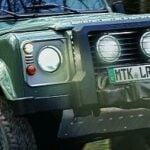 En gröngul Land Rover Defender kör genom skogen. (AI text)