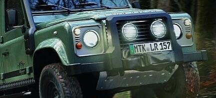 En gröngul Land Rover Defender kör genom skogen. (AI text)