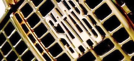 En guldbil med en grille och ett märkeslogo. (AI text)