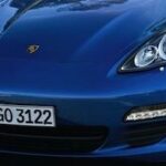 En blå Porsche Cayman kör nerför en väg. (AI text)