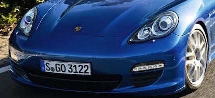 En blå Porsche Cayman kör nerför en väg. (AI text)